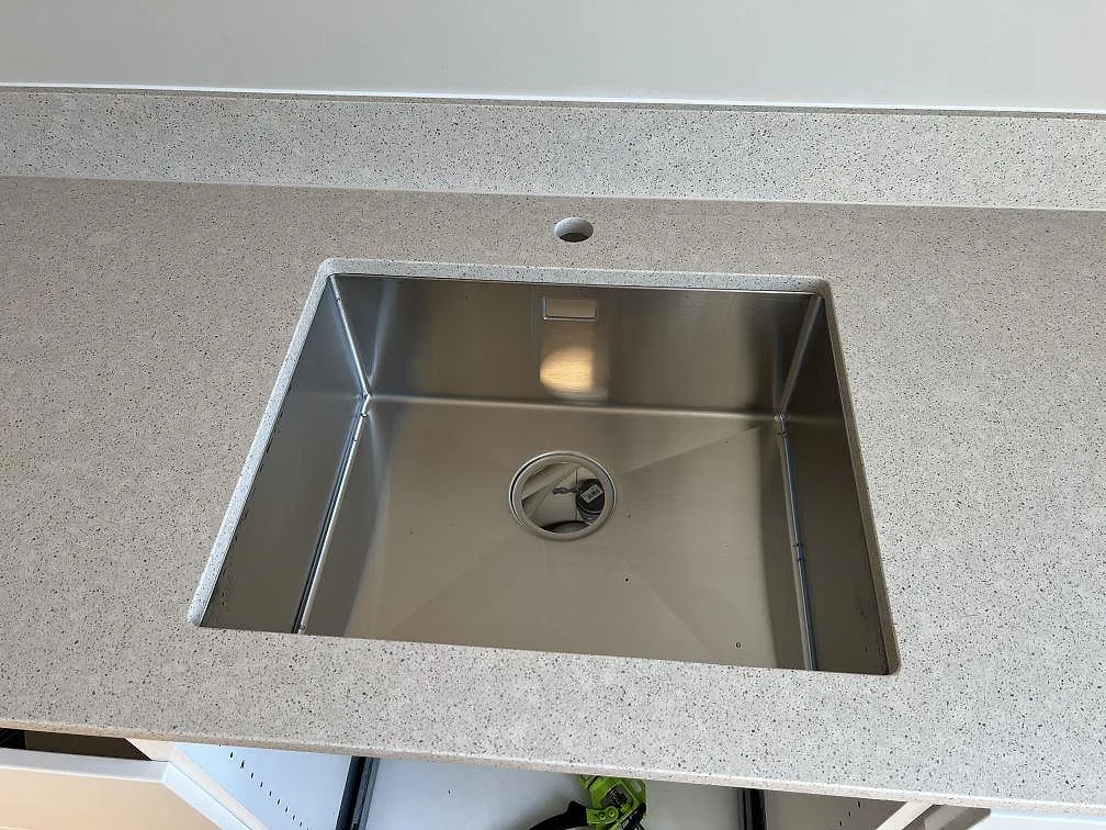 Underlimmad rostfri diskho i en polerad Silestone Blanco City kompositbänkskiva med stänkkant i Bjärred.