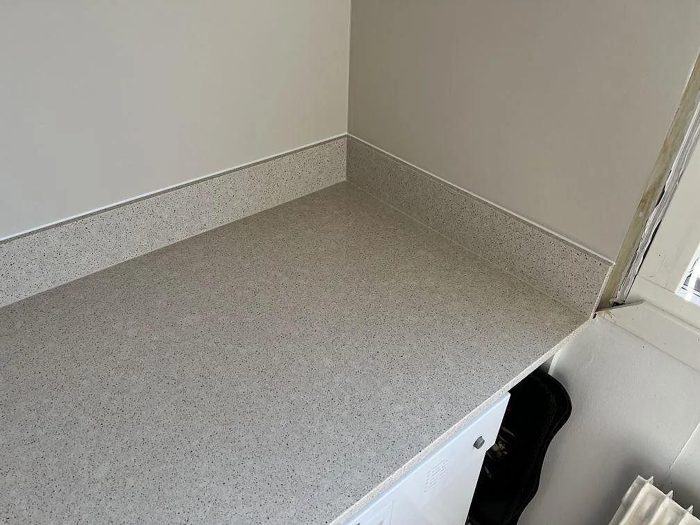 Hörnparti vid fönster med polerad Silestone Blanco City kompositbänkskiva och låg stänkkant i Bjärred.