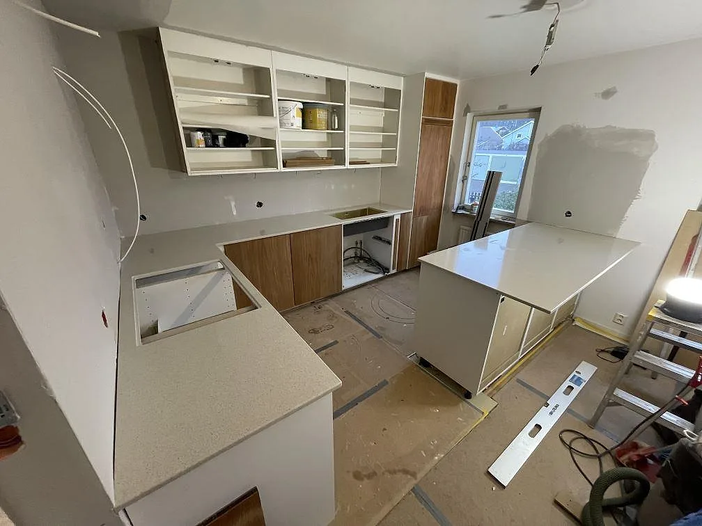 Köksbänkskiva och köksö i polerad Silestone Blanco City, ljus kvartskomposit, under montering i ett kök i Hässelby.