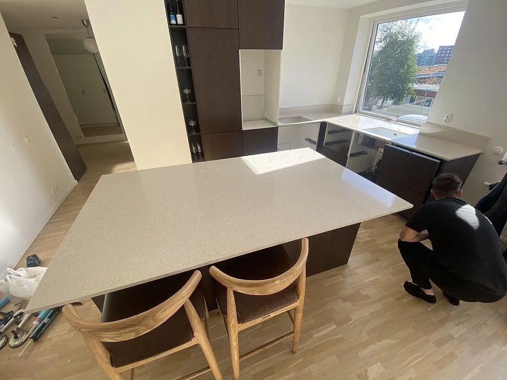 Stor frihängande köksö i vit Silestone Blanco City, polerad komposit, i ett ljust kök under montering i Malmö.
