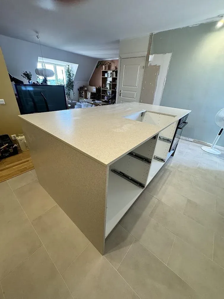 Köksö och bänkskiva i Silestone Blanco City, ljus komposit med matt Mocka-yta, i ett kök under montering i Malmö.