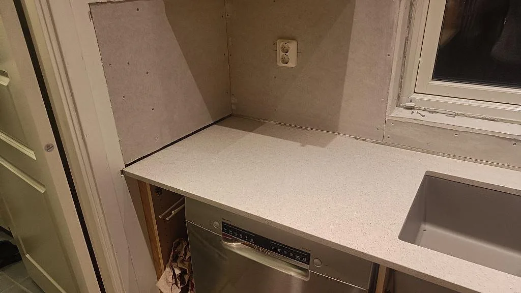 Väggbänk i polerad Silestone Blanco City komposit vid diskho och diskmaskin i ett kök i Malmö.