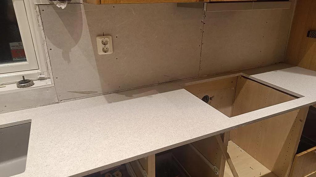 Köksbänkskiva i polerad Silestone Blanco City komposit med rektangulärt urtag under montering i Malmö.