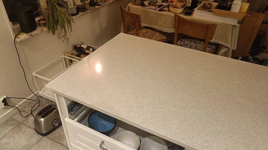 Polerad köksö i Silestone Blanco City komposit med ljus kornig yta i ett kök i Malmö.