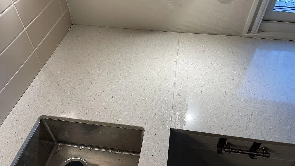 Polerad Silestone Blanco City köksbänkskiva med skarv, rostfri diskho och häll synliga i ett kök i Tygelsjö.