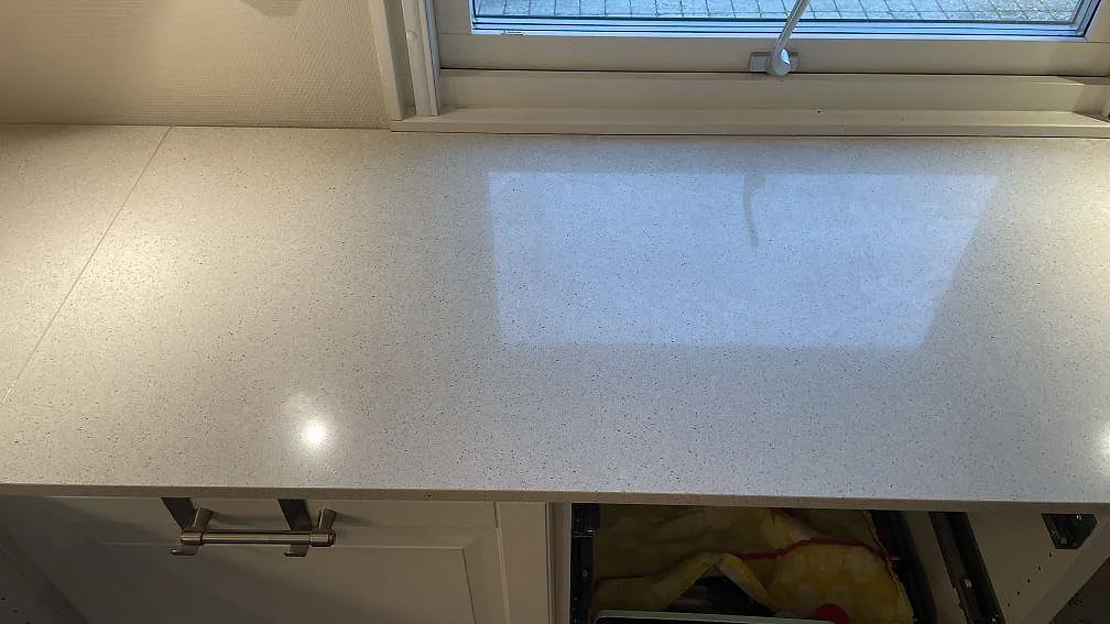 Närbild på polerad Silestone Blanco City kompositbänk med fönsterreflektion och ljus arbetsyta i Tygelsjö.
