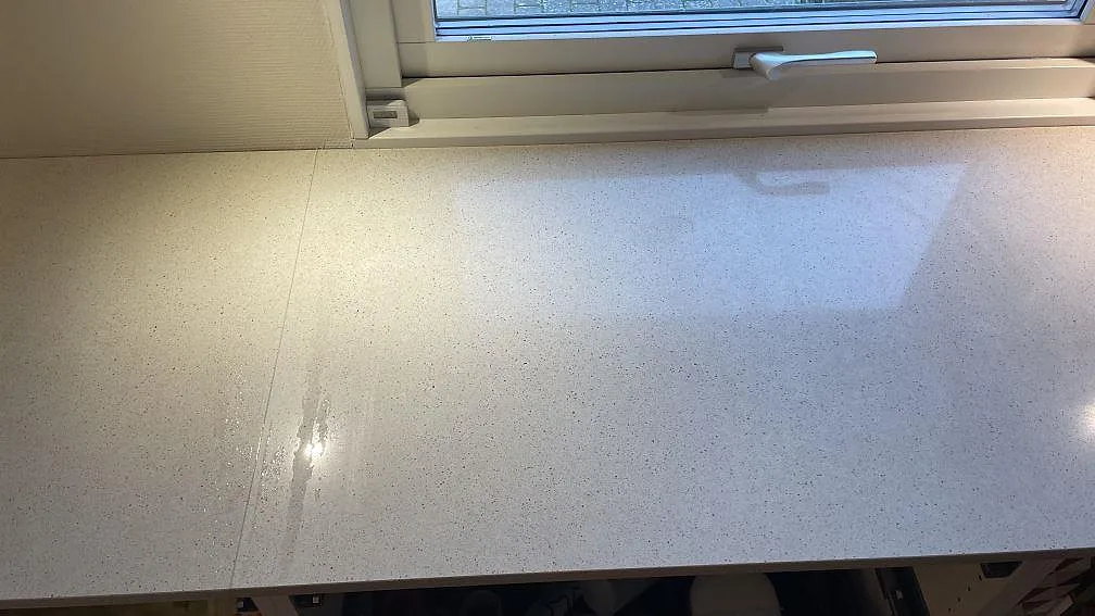 Detalj av ljus Silestone Blanco City bänkskiva, polerad, med skarv och fönsterreflektion i ett kök i Tygelsjö.