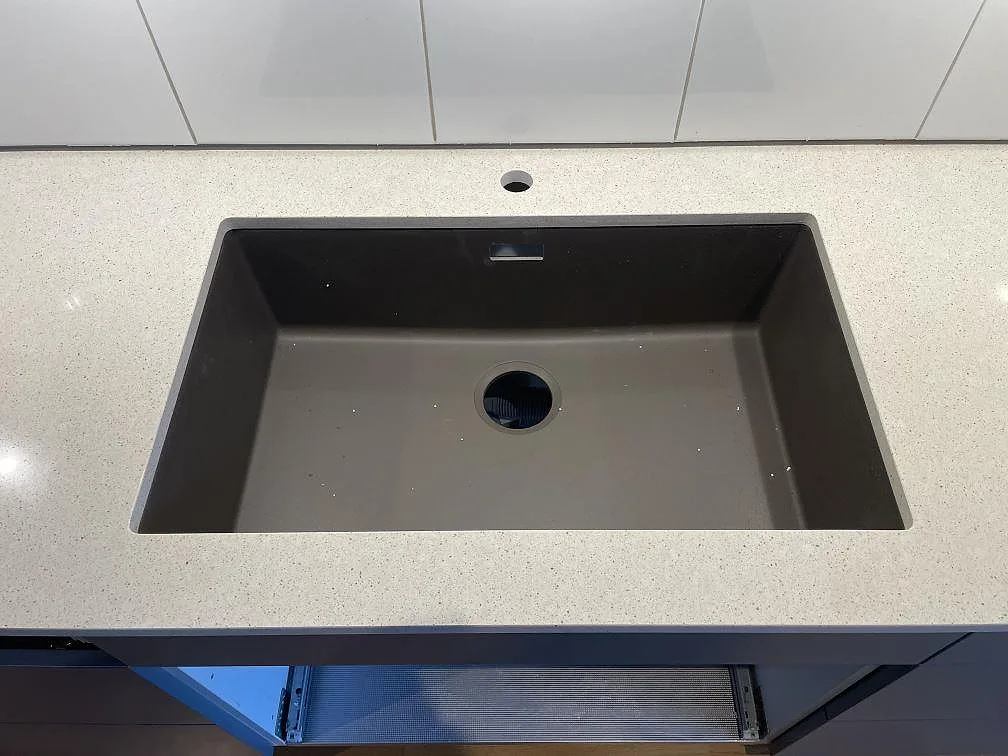 Detalj av mörk diskho i en polerad köksbänkskiva av Silestone Blanco City i Uppsala.