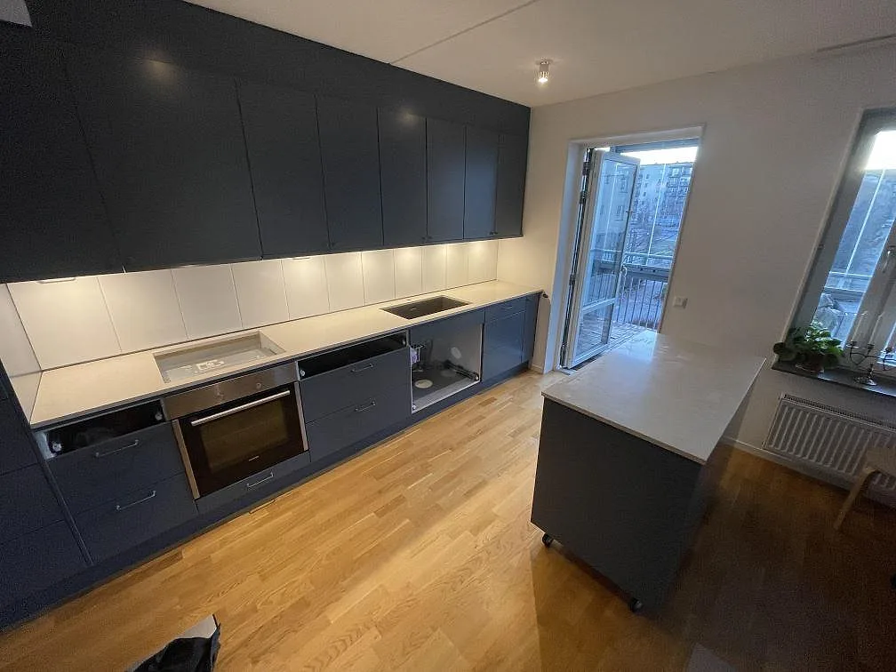 Polerad köksbänkskiva i Silestone Blanco City med ljus kvartskomposit och köksö i ett kök i Uppsala.