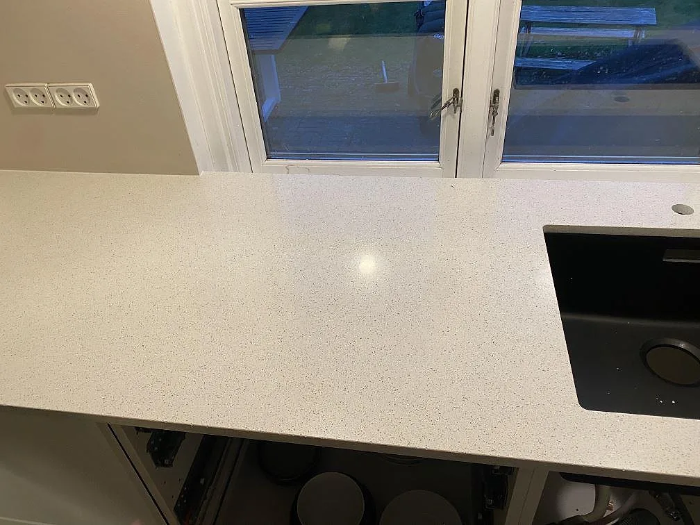 Köksbänkskiva i Silestone Blanco Maple 14, polerad kvartskomposit, med svart underlimmad kompositdiskho längs en fönstervägg i ett kök i Bagsværd.