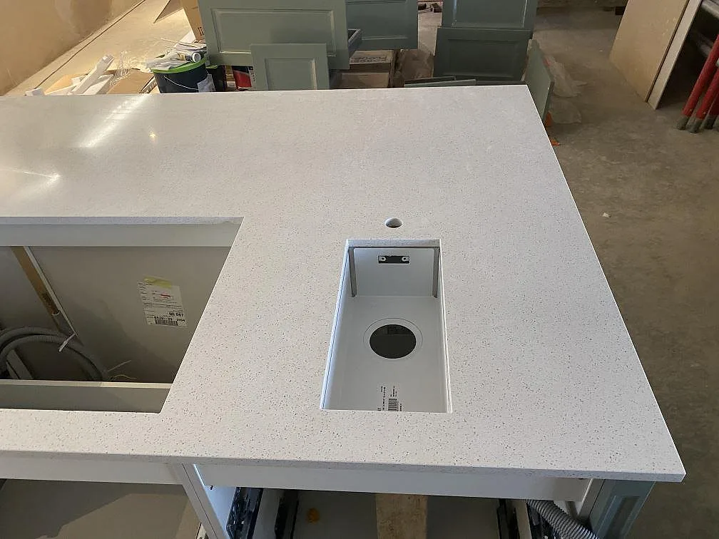 Närbild av köksö i polerad Silestone Blanco Maple 14 med urtag i den vita kompositskivan i Klagshamn.