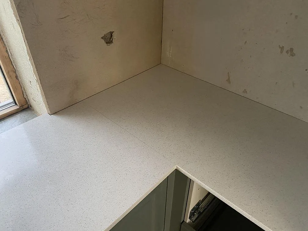 Närbild av monterad köksbänkskiva i Silestone Blanco Maple 14 med polerad vit komposityta och hörnpassning i Klagshamn.