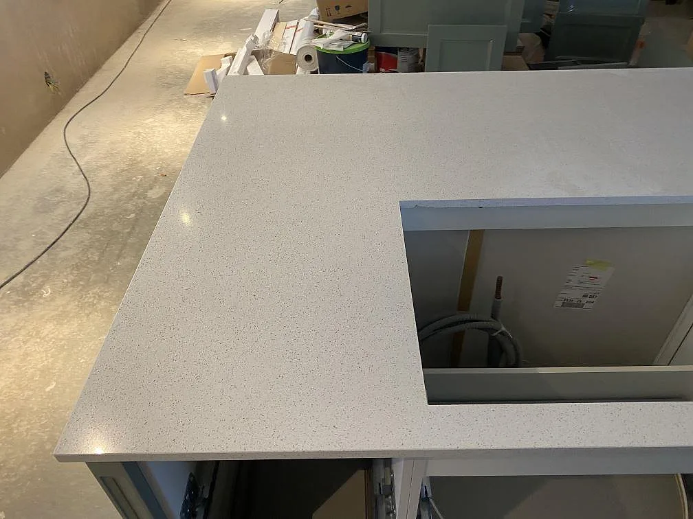 Detalj av vit kompositskiva i Silestone Blanco Maple 14 på köksö med polerad yta och urtag i Klagshamn.