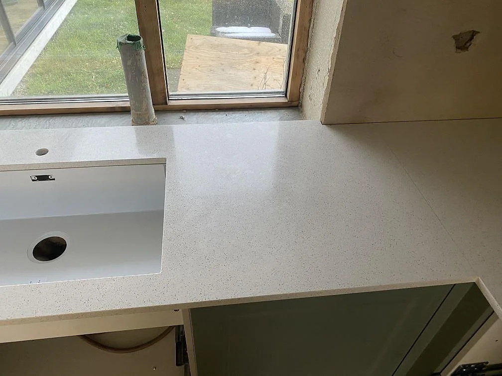 Polerad Silestone Blanco Maple 14 som köksbänkskiva vid fönster, med ljus komposityta i Klagshamn.