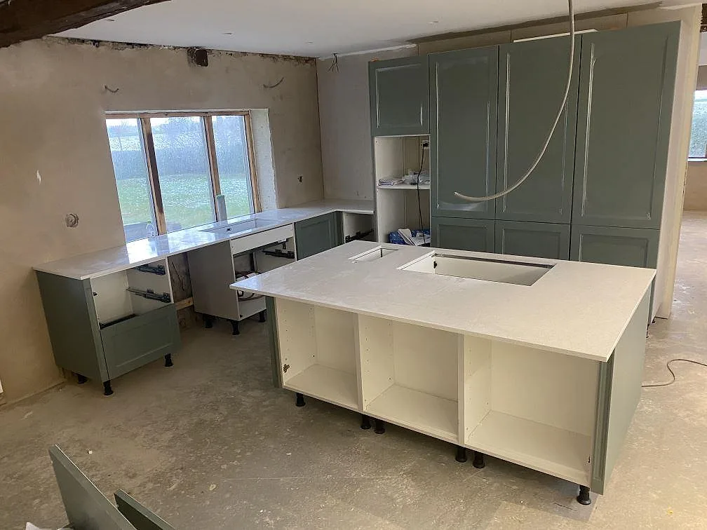 Köksbänkskiva i polerad Silestone Blanco Maple 14 med köksö och perimeterbänk under montering i ett kök i Klagshamn.