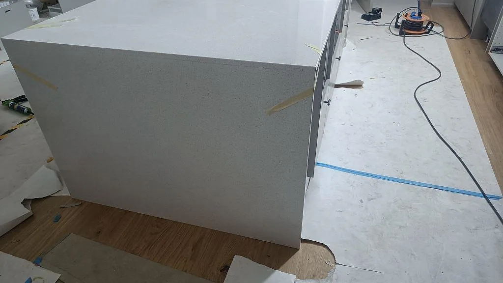 Sidovy av köksö med vit Silestone Blanco Maple 14, polerad yta och skyddad byggarbetsplats i Lund.