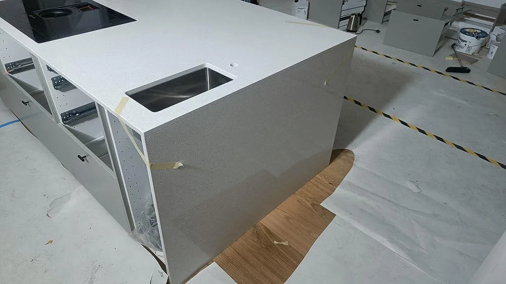 Köksö i vit polerad Silestone Blanco Maple 14 med underlimmad rostfri diskho och svart induktionshäll i Lund.