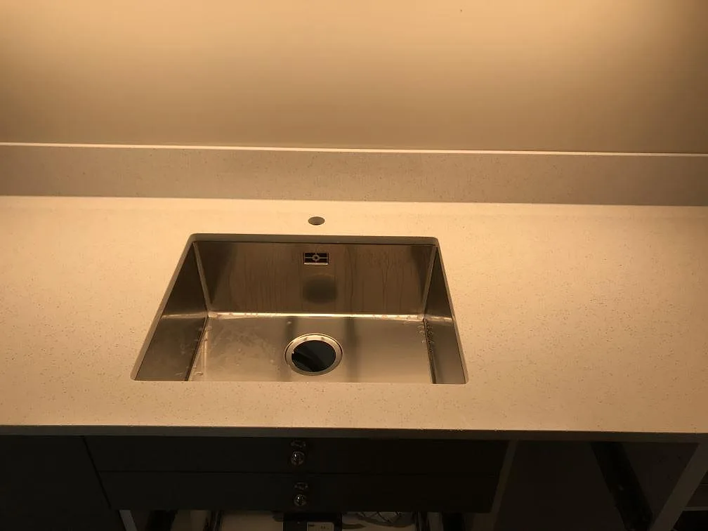 Detalj av underlimmad rostfri diskho i polerad Silestone Blanco Maple 14 med låg stänkkant i Malmö.