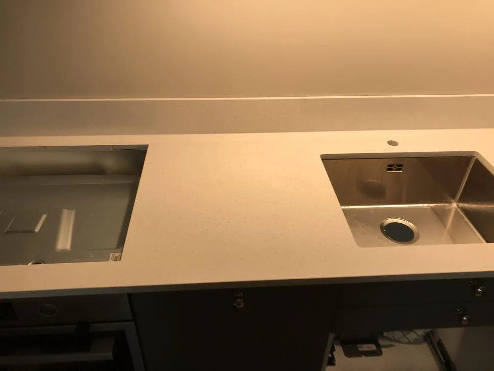 Köksbänkskiva i ljus Silestone Blanco Maple, polerad, med underlimmad rostfri diskho och urtag för diskmaskin i ett kök i Malmö.