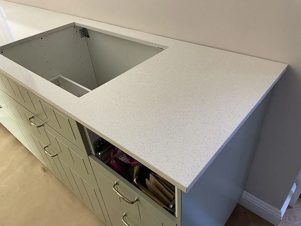 Närbild på diskhozonen i polerad Silestone Blanco Maple 14 med öppna stommar och ljusgröna fronter i ett kök i Malmö.
