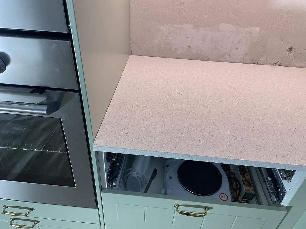 Kort bänkparti i polerad Silestone Blanco Maple 14 vid inbyggnadsugn och rosa vägg under montering i ett kök i Malmö.