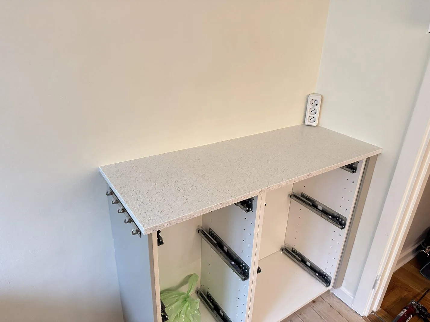 Rak köksbänkskiva i polerad Silestone Blanco Maple 14 över öppna vita stommar under montering i Malmö.