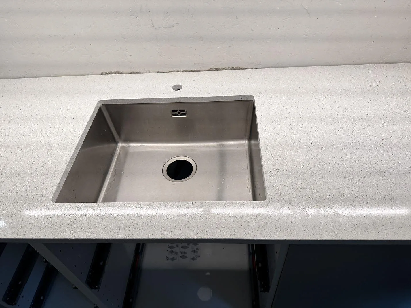Närbild av rostfri diskho monterad under en polerad köksbänkskiva i Silestone Blanco Maple 14 i Malmö.