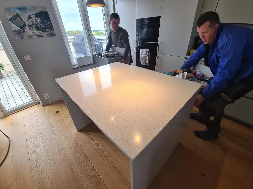 Köksö med bänkskiva i ljus polerad Silestone Blanco Maple 14 komposit under montering i ett kök i Stockholm.