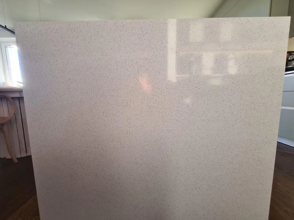 Närbild på gavelsidan av en köksö i polerad Silestone Blanco Maple 14 med fin prickbild i ett kök i Stockholm.
