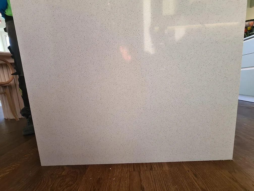Installerad köksö i Silestone Blanco Maple 14, polerad komposit, med vit köksinredning och trägolv i Stockholm.