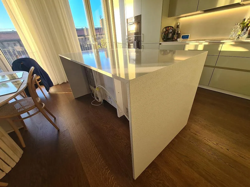 Köksö i vit polerad Silestone Blanco Maple 14, komposit, i ett ljust kök med stora fönster och trägolv i Stockholm.