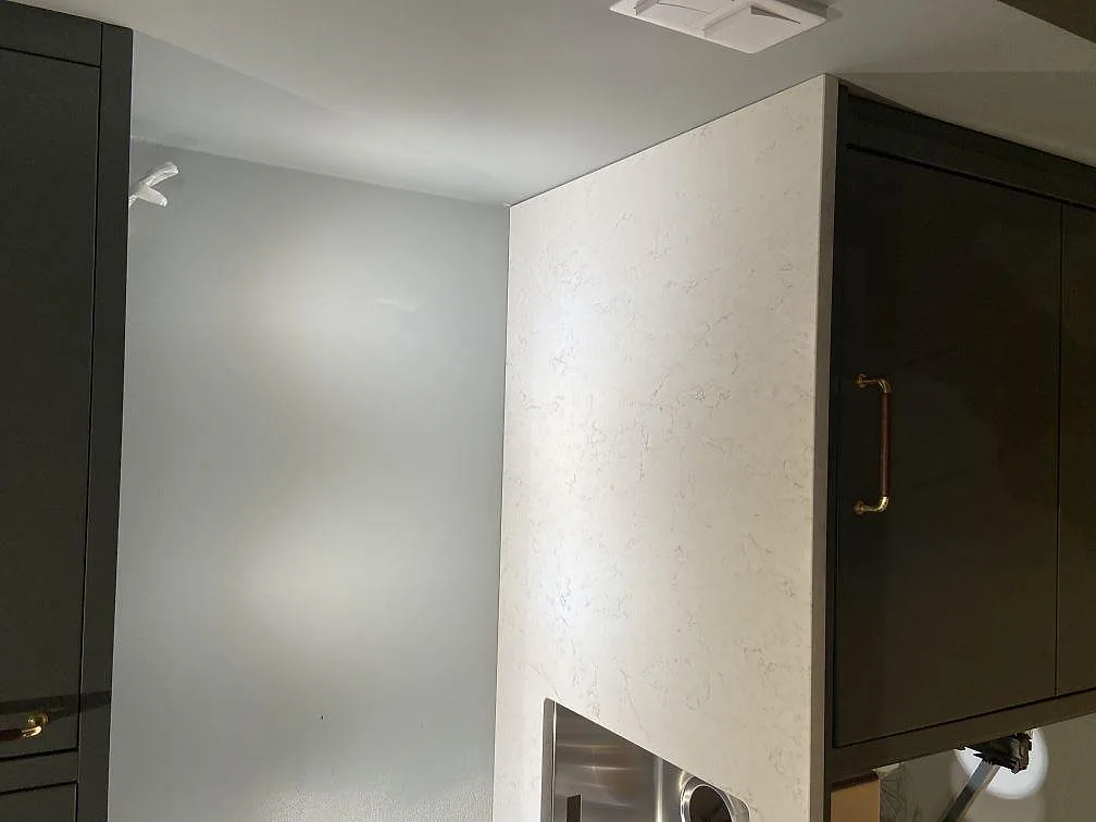 Köksbänkskiva i vit Silestone Blanco Orion, polerad kvartskomposit med grå ådring, med underlimmad rostfri diskho och plats för spishäll i ett kök i Åhus.