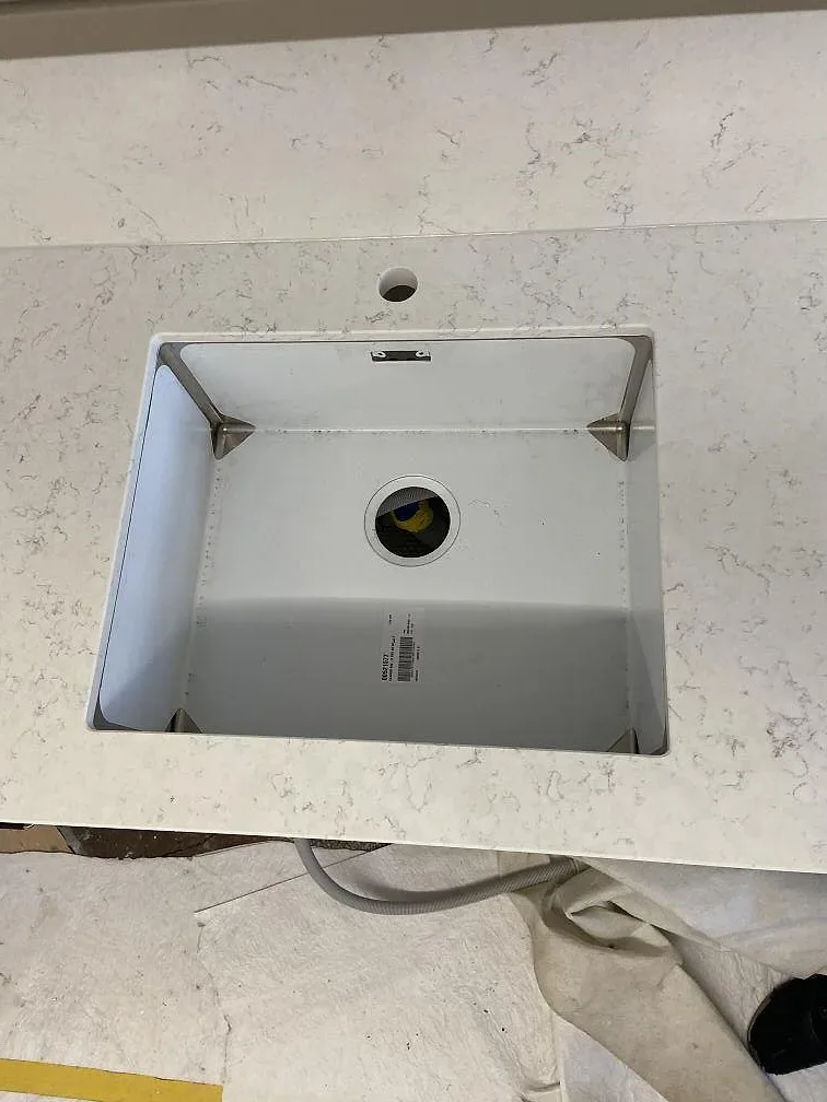 Underlimmad vit enkelho i en köksbänkskiva av Silestone Blanco Orion med separat borrat blandarhål, i ett kök i Göteborg.