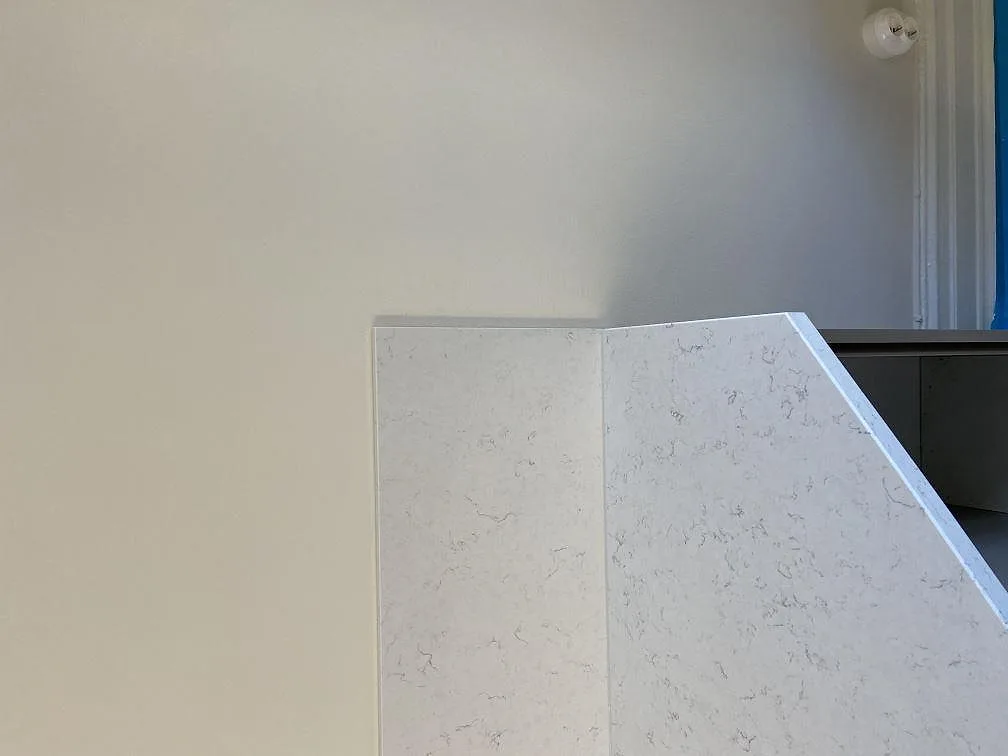 Mitrat gavelparti i benvit Silestone Blanco Orion med diskret grå ådring, en vikt vattenfallskant som faller mot golvet i ett kök i Göteborg.