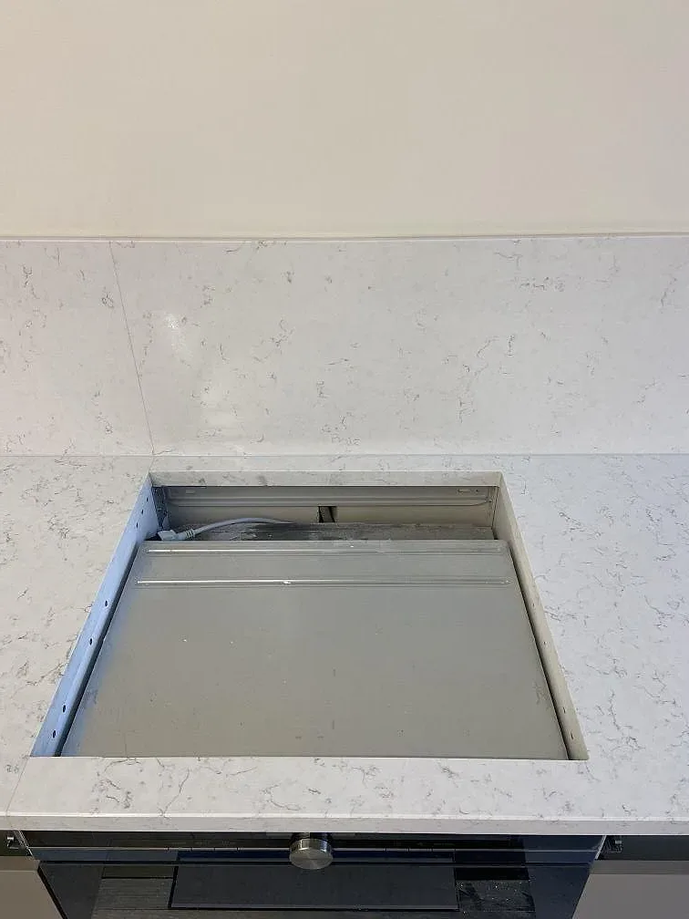 Väggnisch klädd med Silestone Blanco Orion som stänkskydd intill köksbänkskivan i samma vita kvartskomposit i ett kök i Göteborg.
