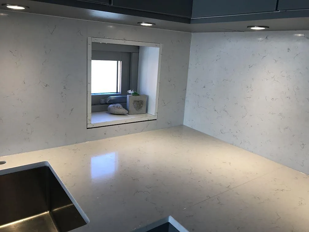 Hörn av bänkskiva i Silestone Blanco Orion med stänkvägg och infälld nisch samt underlimmad rostfri diskho i ett kök i Jönköping.