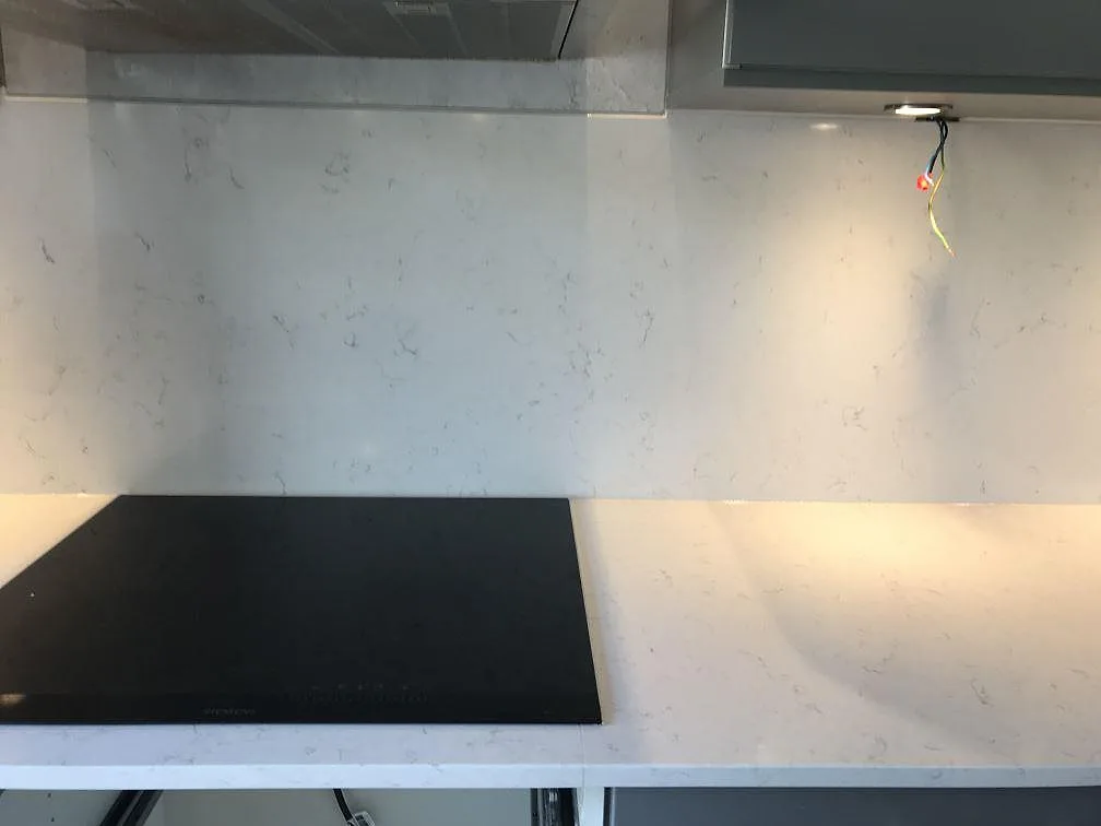Bänkskiva i vit Silestone Blanco Orion med infälld Siemens induktionshäll och stänkvägg i samma kvartskomposit, Jönköping.