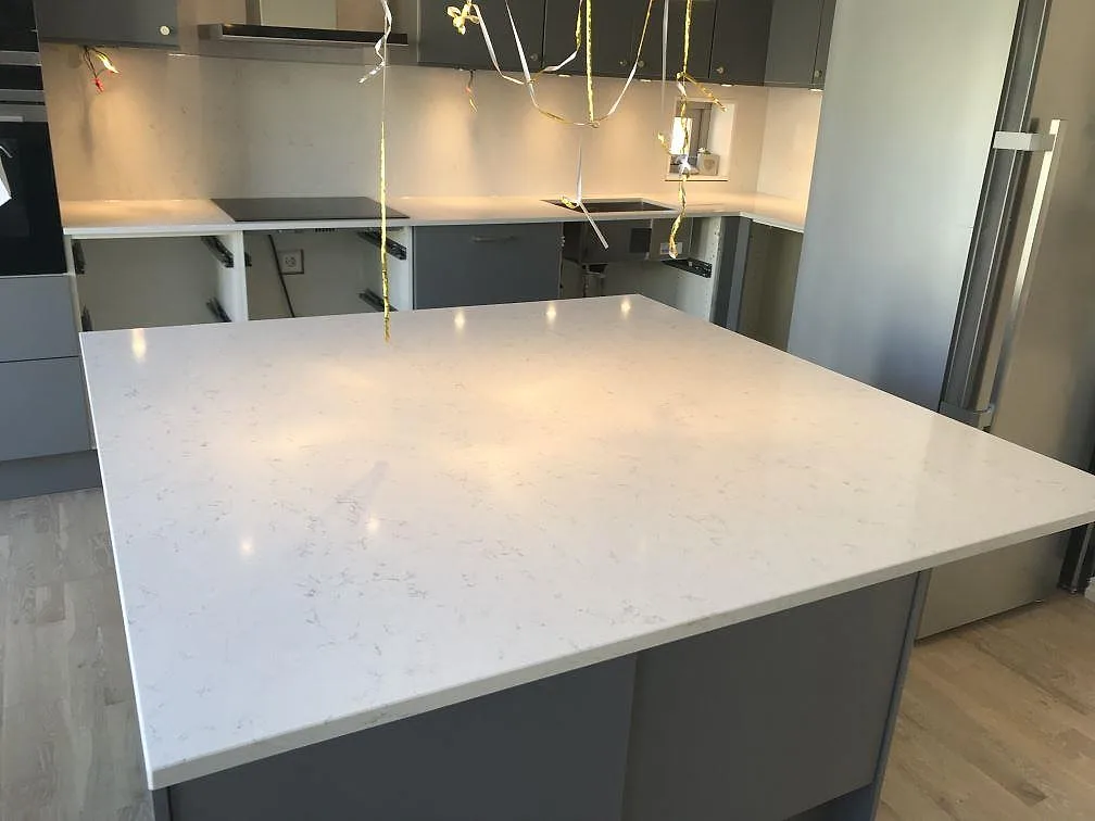 Kök i Jönköping med stor köksö och bänkskivor i vit Silestone Blanco Orion, polerad kvartskomposit med fin grå ådring, fotograferat under montering.