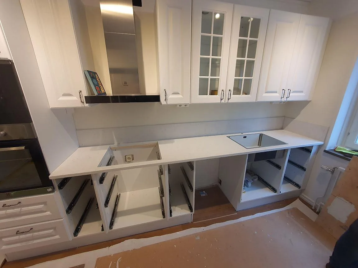 Vit polerad Silestone Blanco Orion kompositbänkskiva med låg stänkkant i ett kök under montering i Johanneshov.