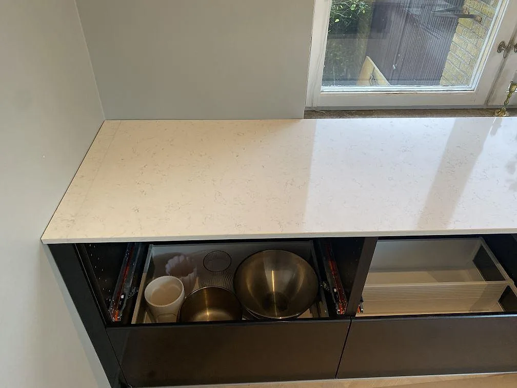 Väggbänk i polerad Silestone Blanco Orion komposit under fönster med mörka köksstommar i Malmö.