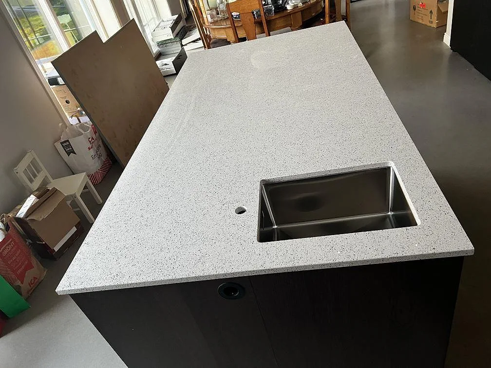 Stor köksö i polerad Silestone Blanco Stellar med underlimmad rostfri diskho och specklad vit komposityta i Tvååker.