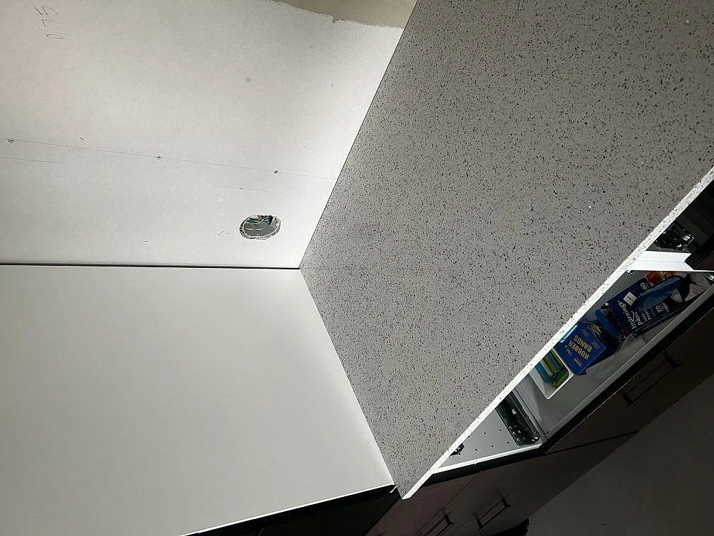 Detalj av kant och yta på polerad Silestone Blanco Stellar, vit kompositbänkskiva under montering i Tvååker.