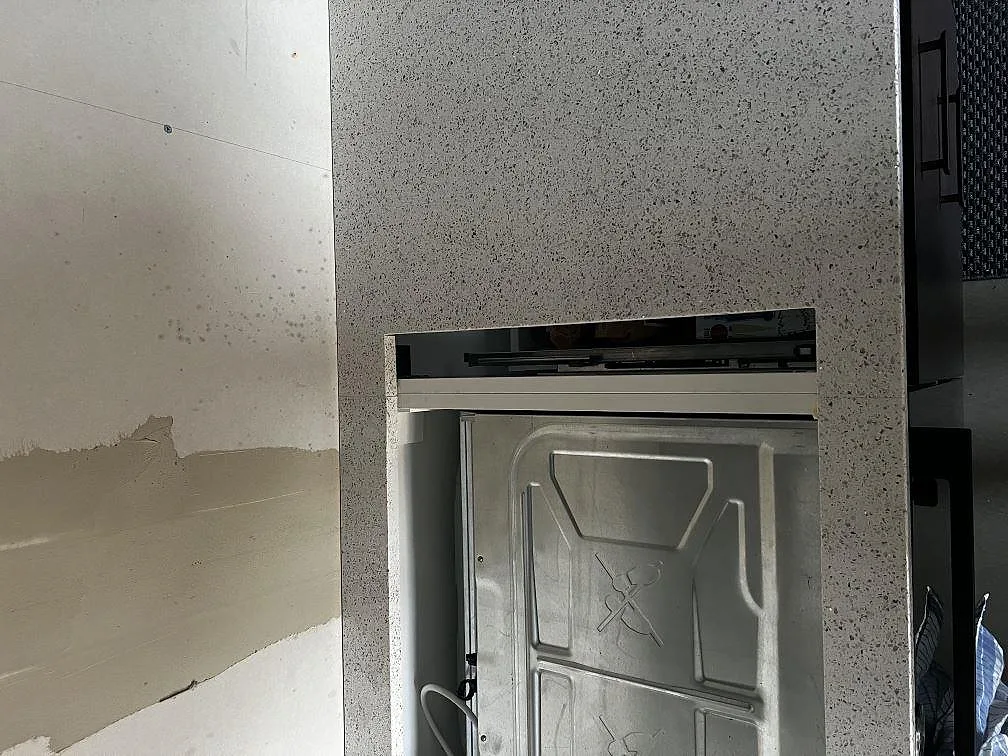 Detalj av polerad Silestone Blanco Stellar runt svart induktionshäll i ett kök under montering i Tvååker.