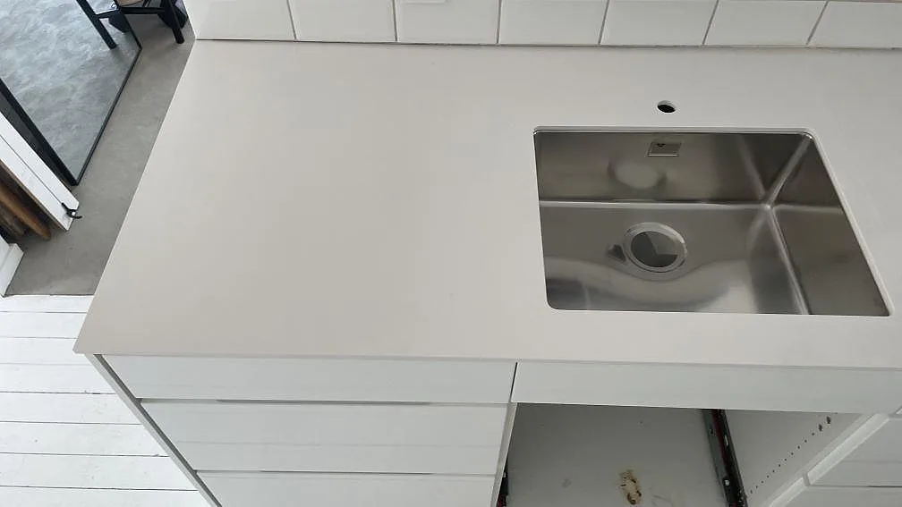 Vit Silestone Blanco Zeus köksbänkskiva i polerad kvartskomposit med diskho och blandarhål under montering i Bunkeflostrand.