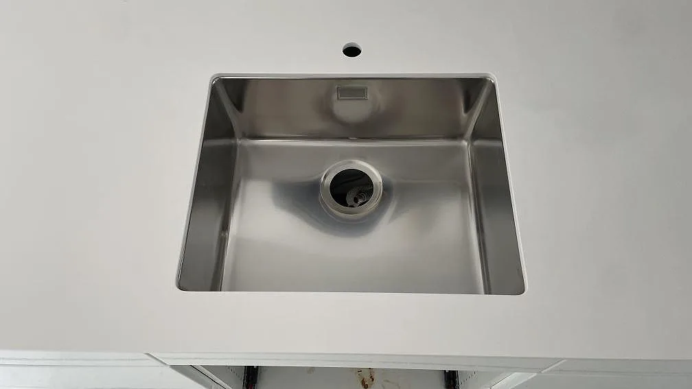 Närbild på rostfri diskho i en vit polerad Silestone Blanco Zeus bänkskiva i kök i Bunkeflostrand.