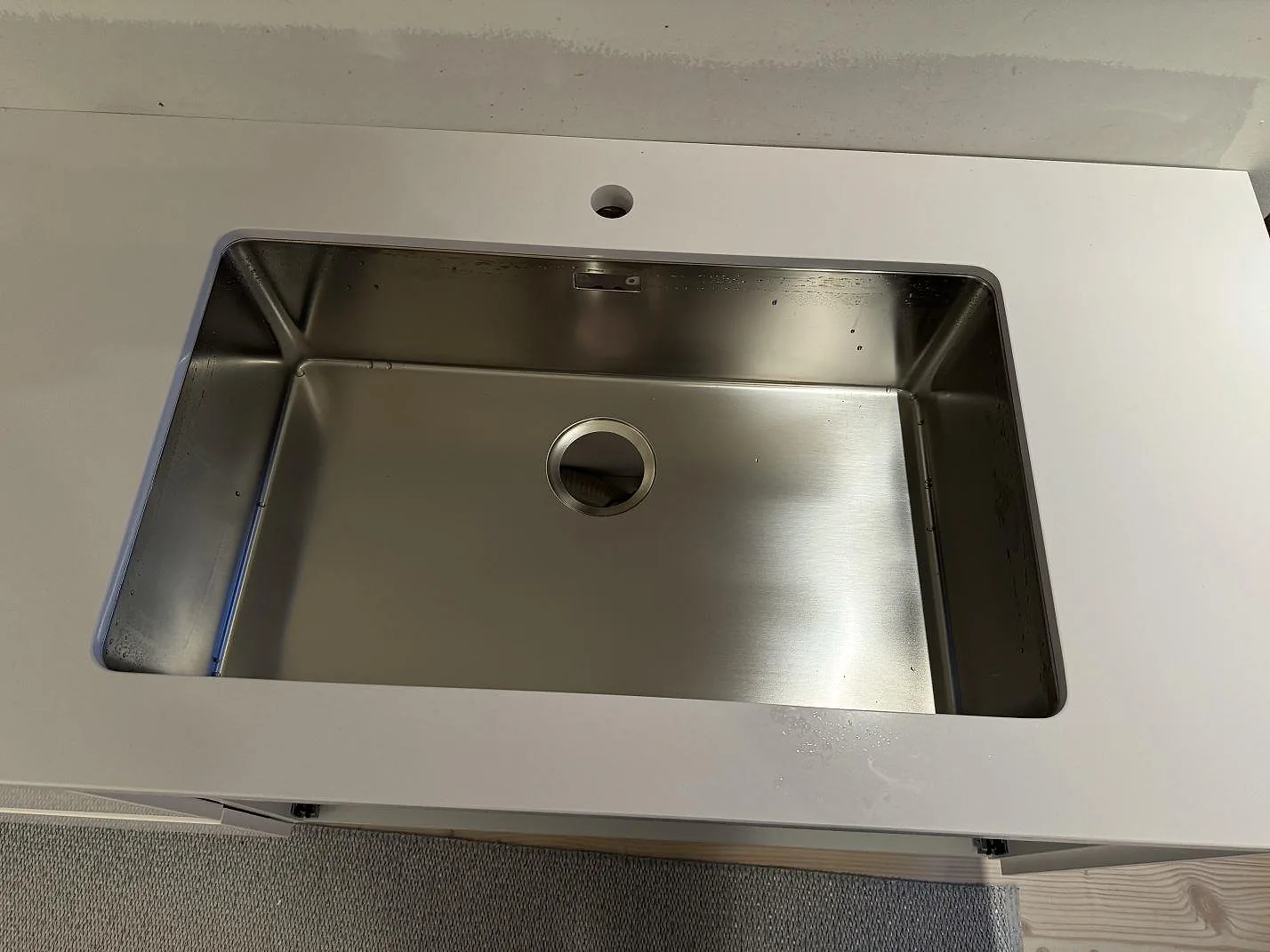 Närbild av underlimmad rostfri diskho i polerad vit Silestone Blanco Zeus Extreme köksbänkskiva i Limhamn.