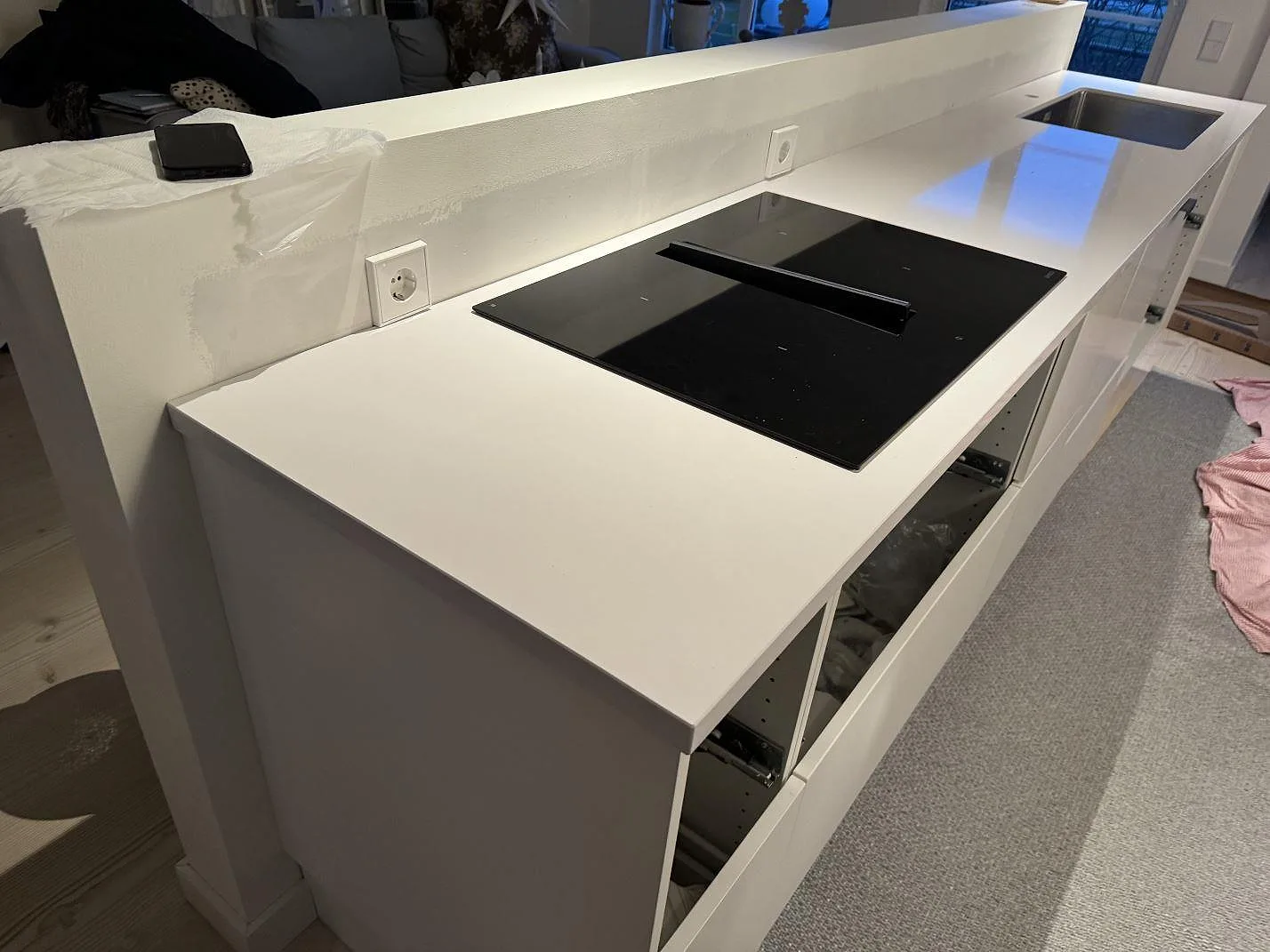 Polerad vit Silestone Blanco Zeus Extreme som köksbänkskiva på en peninsula med häll och rostfri diskho under montering i Limhamn.