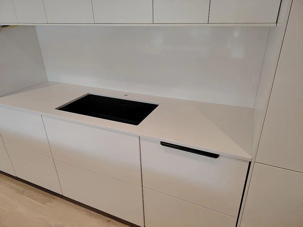 Väggbänk i vit Silestone Blanco Zeus, polerad kvartskomposit, med svart häll och matchande stänkskydd i ett kök i Västerås.