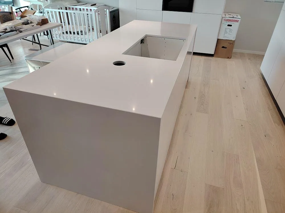 Polerad köksö i Silestone Blanco Zeus med urtag för diskho och blandare i ett ljust kök under montering i Västerås.