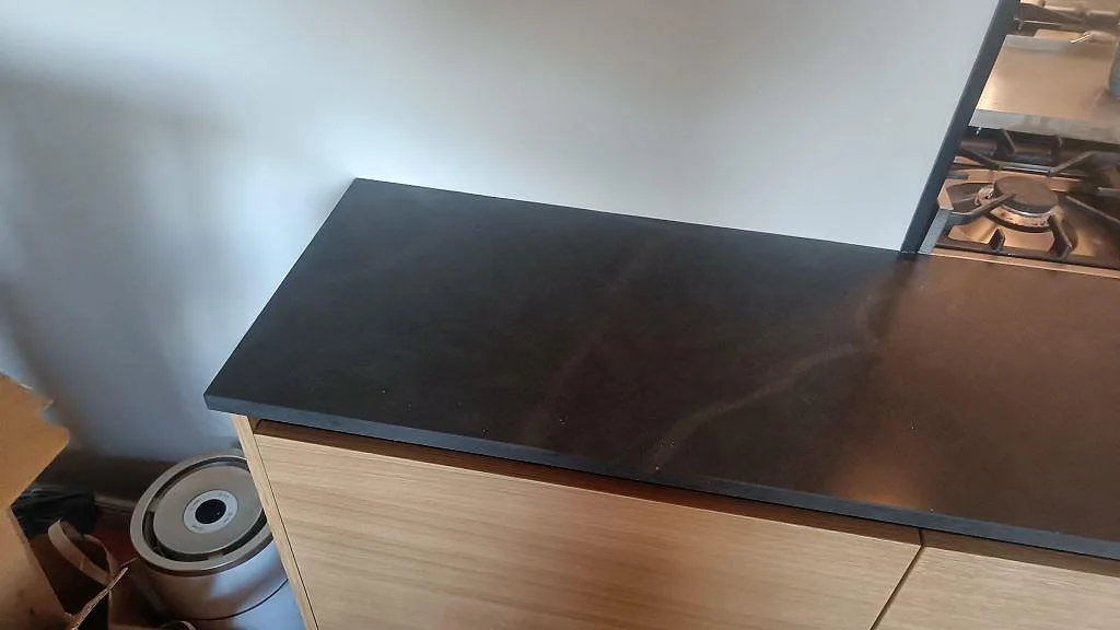 Installerad köksbänkskiva i matt Silestone Bohemian Flame på träinredning, med mörk komposityta och mjuk ådring i Kävlinge.